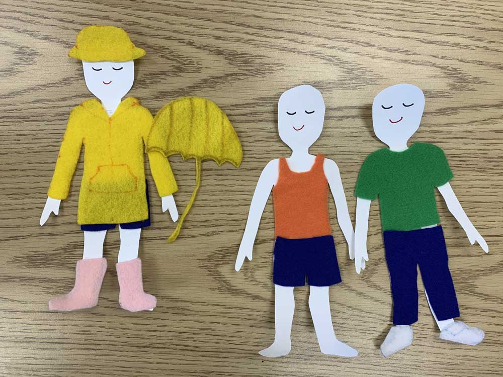 A group of paper people with one holding an umbrella.